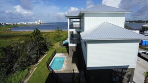 Una casa de dos pisos con piscina, vista al océano y un muelle para embarcaciones.
