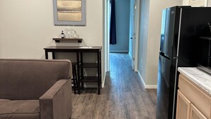 A modern kitchen with a black refrigerator, wooden cabinets, and a dining area with a table and chairs. - 'Mother-In-Law' apartment in rural neighborhood.King bed, Kitchenette, fullbath. (Wasilla)