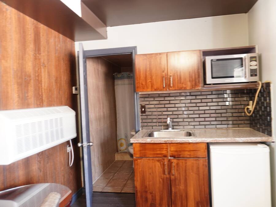 A compact kitchen with wooden cabinets, a microwave, and a sink.