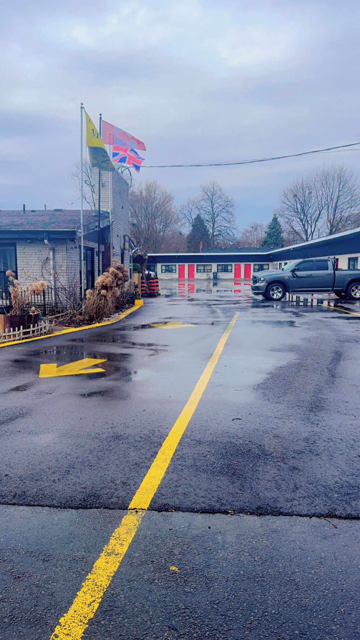 Un estacionamiento con una línea amarilla, una bandera y un edificio con puertas rojas.
