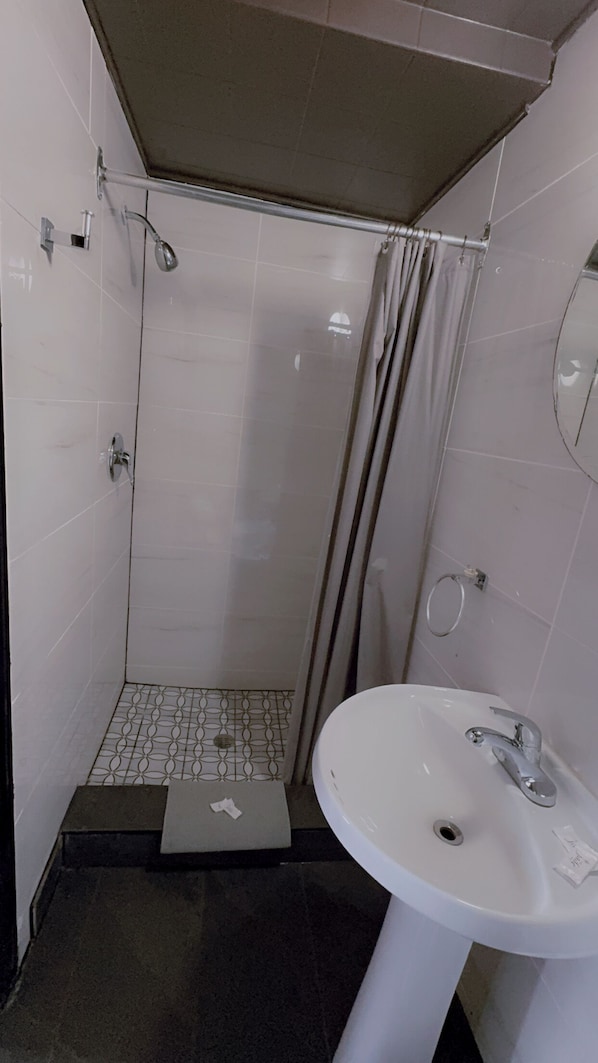 A small, tiled bathroom with a shower, a sink, and a toilet. - crestwoodmotel (Burlington)