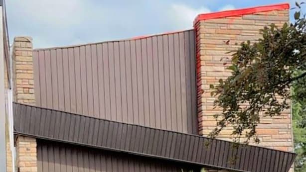 A house with a sloped roof, a brick chimney, and a wooden fence. - crestwoodmotel (Burlington)