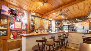 A bar with wooden decor, a counter, and stools. - The Downtown Historic Island Hotel (Cedar Key)