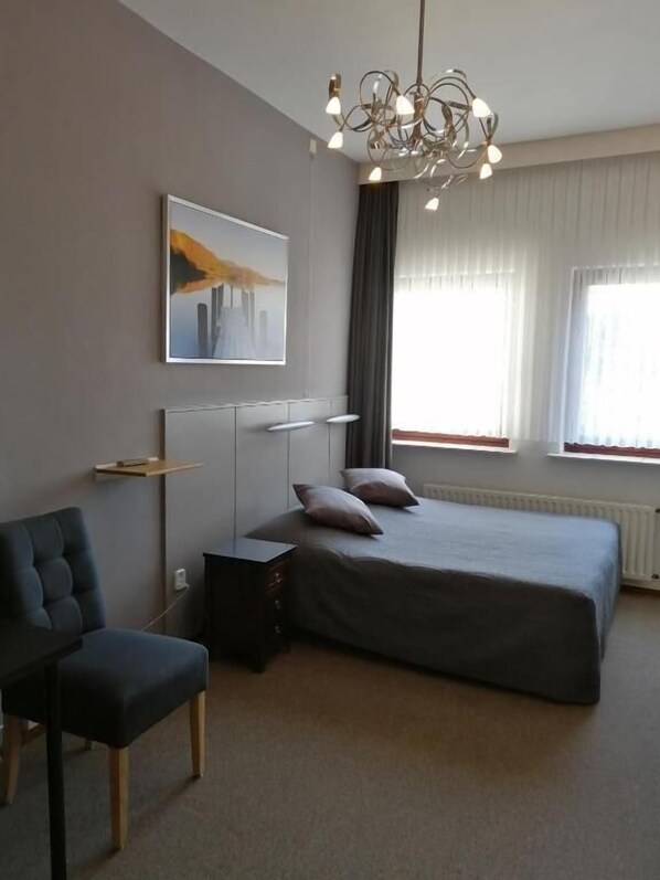 A modern bedroom with a large bed, a chair, a desk, and a unique chandelier. - Hotel Heynen (Valkenburg aan de Geul)