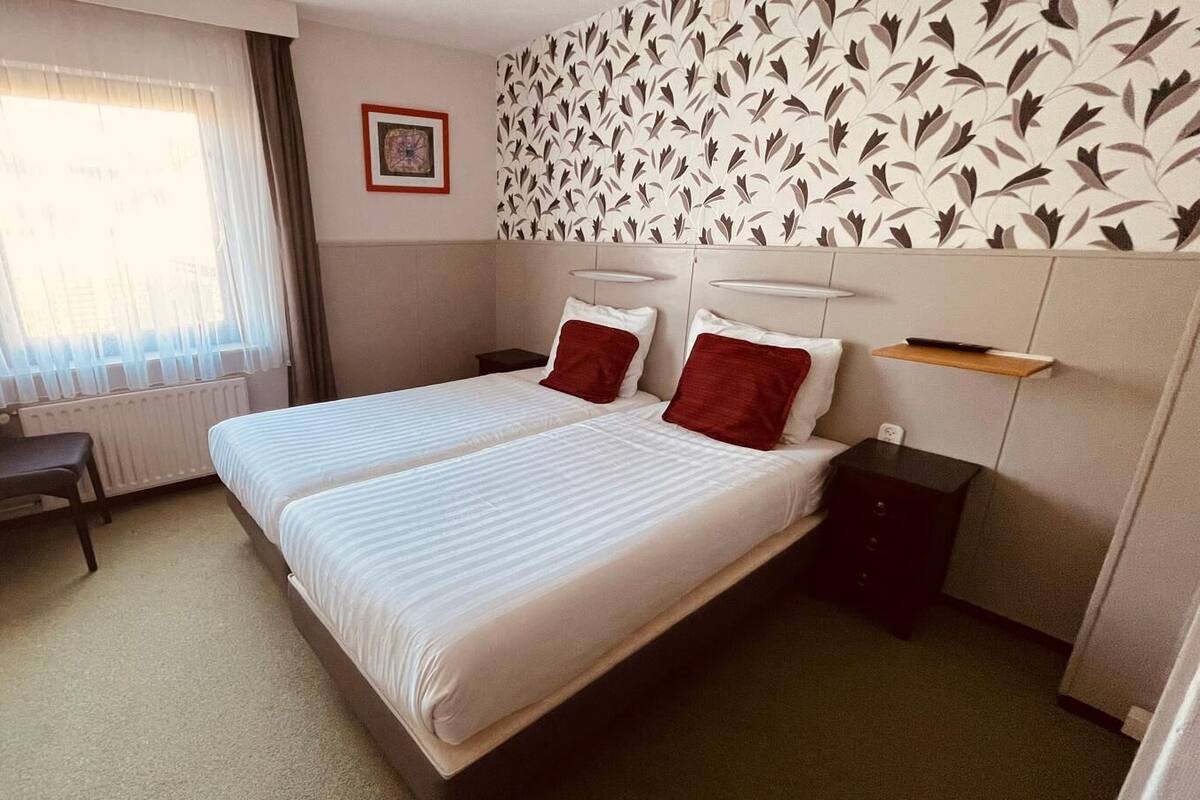 Een hotelkamer met twee bedden, een bureau, een stoel en een radiator.