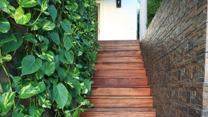 Eine Holztreppe mit einer Mauer aus Ziegelsteinen auf einer Seite und einer grünen, mit Pflanzen bewachsenen Wand auf der anderen.
