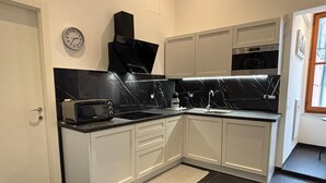 A modern kitchen with white cabinets, a black countertop, a microwave, and a built-in oven.