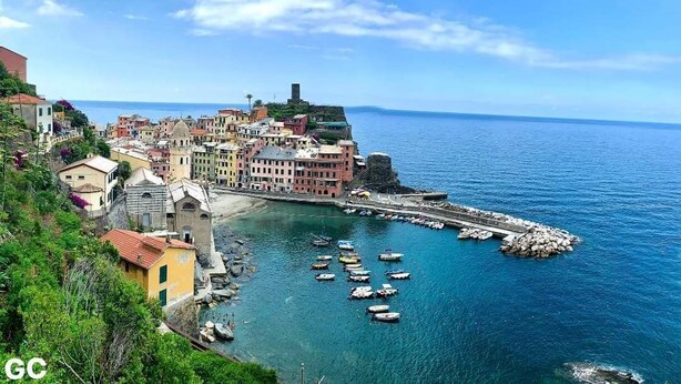 A coastal town with colorful buildings, a historic fort, and a marina with boats.