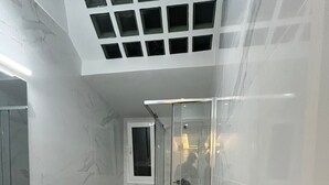 Moderni kylpyhuone, jossa on lasiseinällä varustettu suihku, wc ja pesuallas.