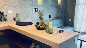 Eine moderne Küche mit Betonarbeitsplatte, einer Obstschale, einer Flasche und einer Sonnenbrille.