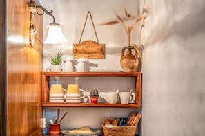 Una repisa con utensilios de cocina, un letrero colgante y un florero con plantas secas.