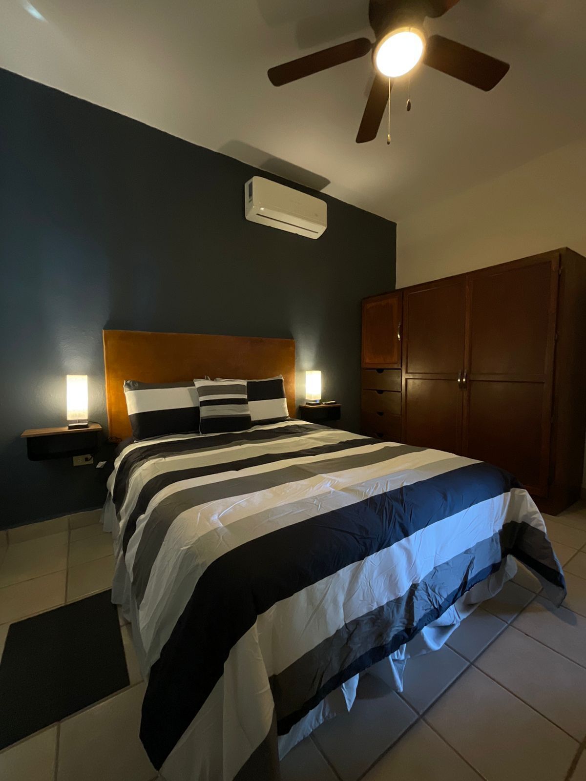 Ein Schlafzimmer mit einem Bett, Nachttischen, einem Deckenventilator und einem Kleiderschrank.