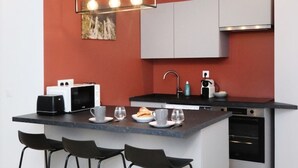 A modern kitchen with a central island, a microwave, a sink, and a built-in oven. - Notre Dame de Senlis par La Boite en plus (Senlis)