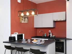 Une cuisine moderne dotée d’un îlot central, d’un four à micro-ondes, d’un évier et d’un four encastré.