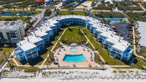 Un hôtel moderne doté d’une piscine centrale entourée d’espaces de détente, de plusieurs étages et situé en bord de mer.