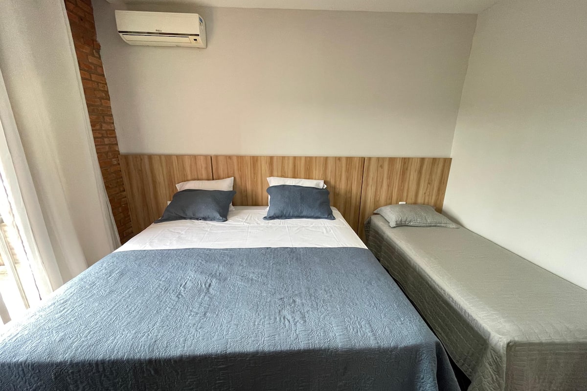 Ett hotellrum med en stor säng, en mindre säng och en sänggavel i trä.
