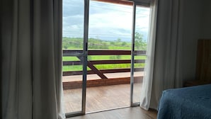 A room with a large sliding glass door leading to a balcony with a wooden railing. - Hotel Villa Green  (Tome-Acu)
