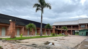 A building with a brick exterior, a covered walkway, and a palm tree. - Hotel Villa Green  (Tome-Acu)
