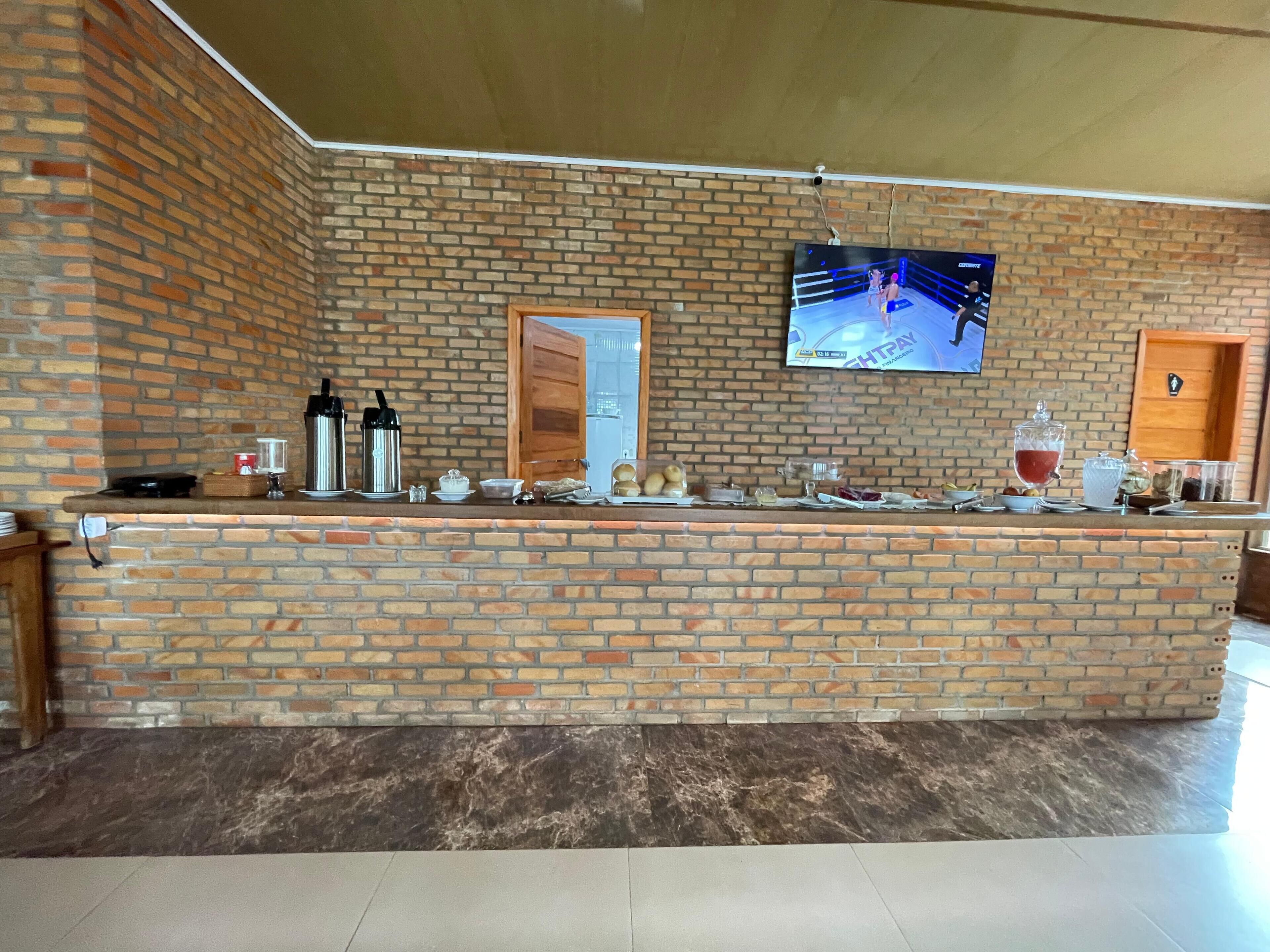 Un mostrador de ladrillo con un televisor montado en la pared, una puerta de madera y varios objetos sobre el mostrador.