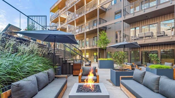 An outdoor seating area with a fire pit, sofas, and planters.