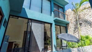 Un bâtiment moderne doté de grandes fenêtres en verre, d’un balcon et d’un mur en pierre.