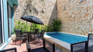 Un espace piscine agrémenté d’un mur en pierre, de mobilier d’extérieur et d’une piscine carrelée.