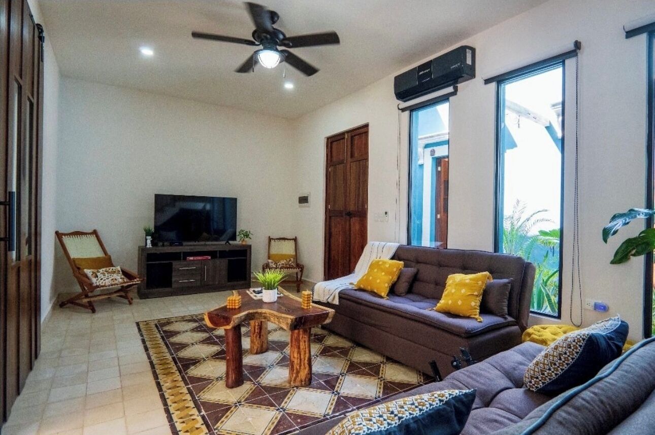 A living room with a sofa, TV, wooden coffee table, and a patterned rug.