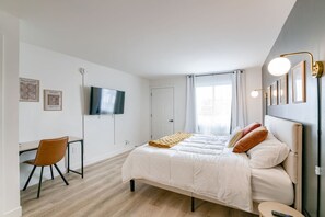 A bedroom with a bed, a desk, a chair, a TV, and a window. - 5 min. to Lincoln's top attractions. King-size bed, kitchenette & outdoor space (Lincoln)