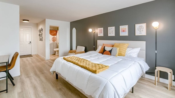 A modern bedroom with a large bed, bedside tables, a desk, and a chair. - 5 min. to Lincoln's top attractions. King-size bed, kitchenette & outdoor space (Lincoln)