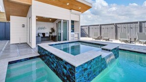 A modern outdoor pool area with a wooden ceiling, a seating area with a sofa and chairs, and a view of the sky.