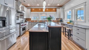 A modern kitchen with stainless steel appliances, a large island, and wooden flooring.