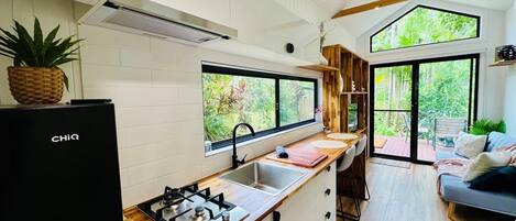 Una cocina moderna con estufa a gas integrada, un lavamanos y ventana con vistas a un jardín.