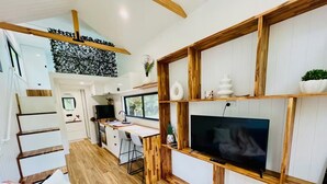 Une cuisine moderne dotée d’un plan de travail en bois, d’un téléviseur encastré et d’un coin repas avec une table et des chaises en bois.