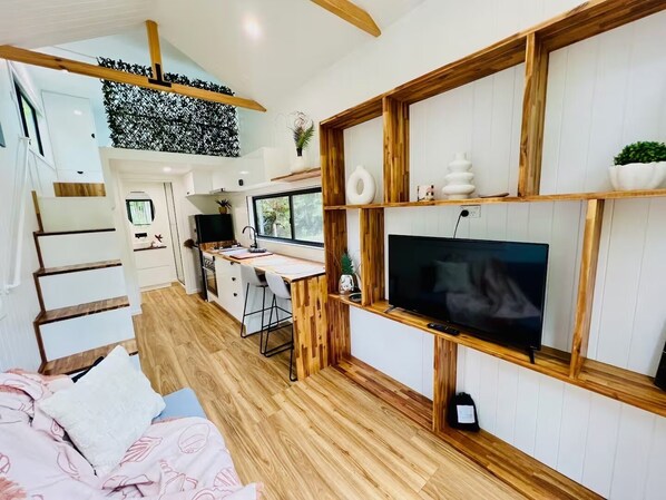Une cuisine moderne dotée d’un plan de travail en bois, d’un téléviseur encastré et d’un coin repas avec une table et des chaises en bois.