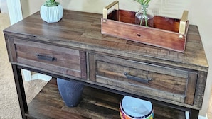 A wooden desk with two drawers, a vase with an orange flower, and a round mirror on the wall. - Paradise Quarters Walk-in Suite at the Legacy at Thousand Hills! Great Rates! (Branson)