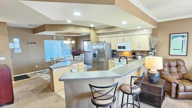 A modern kitchen with a central island, bar stools, a brown leather armchair, and a lamp. - Paradise Quarters Walk-in Suite at the Legacy at Thousand Hills! Great Rates! (Branson)