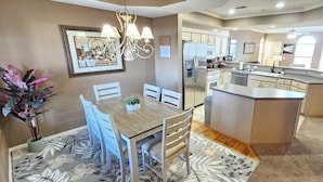 A modern kitchen with a central island, white cabinetry, and a dining area with a wooden table and chairs. - Paradise Quarters Walk-in Suite at the Legacy at Thousand Hills! Great Rates! (Branson)