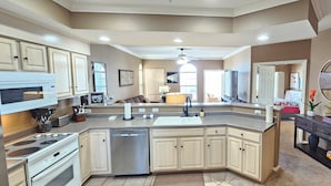 A modern kitchen with a central island, built-in appliances, and a dark wooden console table. - Paradise Quarters Walk-in Suite at the Legacy at Thousand Hills! Great Rates! (Branson)