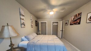 A bedroom with a bed, a bedside table with a lamp, and a ceiling fan. There are doors leading to other rooms. - Spacious 4-bdr house in charming Del City with AC, WiFi and 9 min of Tinker AFB (Del City)