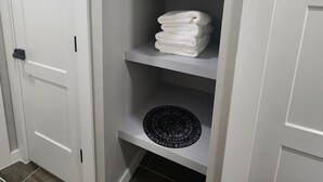 A white closet with multiple shelves, a small decorative item on the top shelf, and a black circular object on the bottom shelf. - Spacious 4-bdr house in charming Del City with AC, WiFi and 9 min of Tinker AFB (Del City)