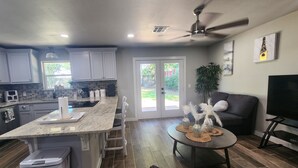 A modern kitchen with white cabinets, a granite countertop, and a dining area with a round table. - Spacious 4-bdr house in charming Del City with AC, WiFi and 9 min of Tinker AFB (Del City)