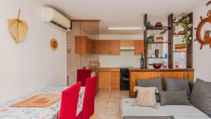 Ett kompakt bostadsutrymme med ett litet kök, en matplats och en sittgrupp med en soffa och stolar.