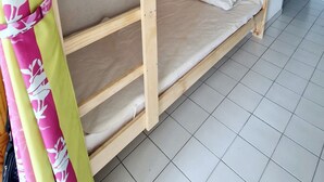 A bunk bed with two levels, a plain wall, and a tiled floor. - Two-room flat, Le Grau du Roi (Le Grau-du-Roi)