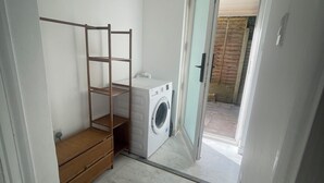 Une buanderie équipée d’un lave-linge, d’un étendoir et d’un banc en bois.