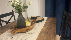 Une table de salle à manger en bois, ornée d’un vase de fleurs et d’une bougie.