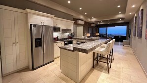 A modern kitchen with a large island, built-in appliances, and a view to the outside. - Private Jacuzzi w/  Ocean Views, Copala Quivira - 20% off F & B - 3 Bed (Cabo San Lucas)