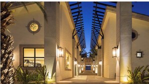 A corridor with a ceiling structure, palm trees, and wall-mounted light fixtures. - Private Jacuzzi w/  Ocean Views, Copala Quivira - 20% off F & B - 3 Bed (Cabo San Lucas)