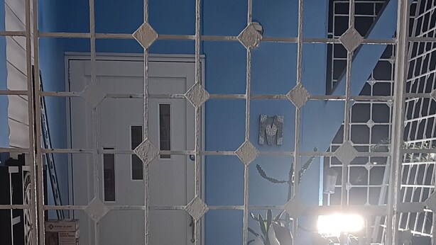 A room with a blue wall, a white door, and a metal gate.