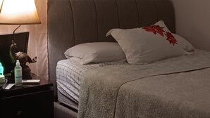 A bedroom with a bed, a nightstand, a lamp, and an air conditioning unit.
