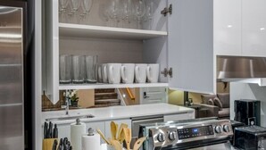 Una cucina moderna con mobili bianchi, un frigorifero in acciaio inossidabile, forno integrato e un tostapane.